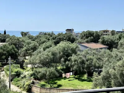 a view of a garden with trees and the ocean at Akhdar Apartments in Utjeha