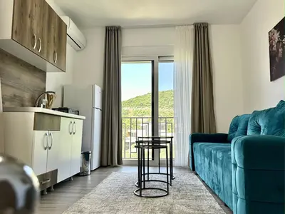 a living room with a blue couch and a kitchen at Akhdar Apartments in Utjeha