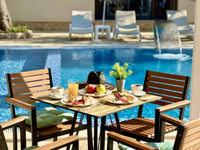 a table with food on it next to a pool at Akhdar Apartments in Utjeha