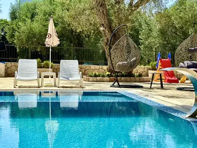 a swimming pool with two chairs and an umbrella at Akhdar Apartments in Utjeha