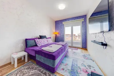 a purple couch in a room with a window at Plum Apartment in Podgorica