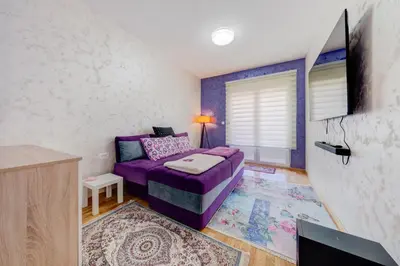 a living room with a purple couch and a tv at Plum Apartment in Podgorica