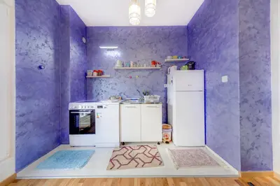 a purple kitchen with a stove and a refrigerator at Plum Apartment in Podgorica