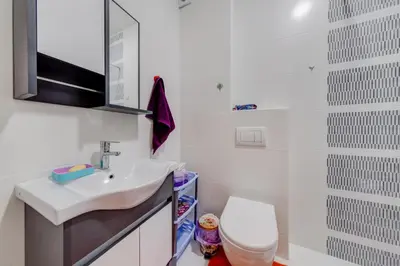 a white bathroom with a sink and a toilet at Plum Apartment in Podgorica