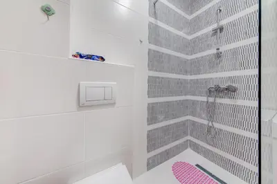 a bathroom with a shower with gray tiles at Plum Apartment in Podgorica