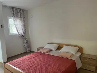 a bedroom with a bed with a red comforter and a window at SeaAdrik in Bar