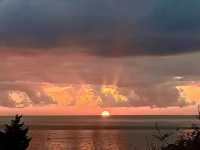 a sunset over the ocean with the sun in the clouds at SeaAdrik in Bar