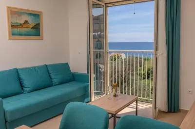 a living room with a couch and a view of the ocean at Apartments Bonazza in Petrovac na Moru