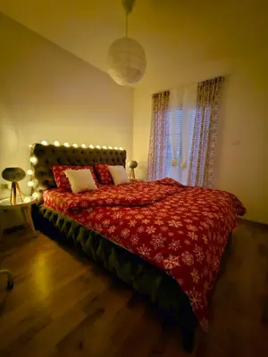 a bedroom with a bed with a red comforter at Apartman AURORA CETINJE in Cetinje