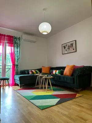 a living room with a green couch and a colorful rug at Apartman AURORA CETINJE in Cetinje