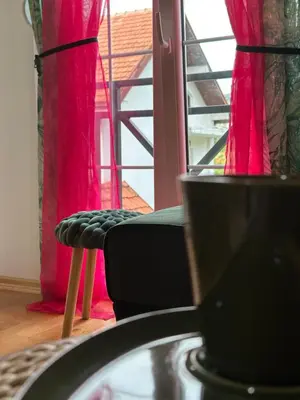 a room with pink curtains and a chair in front of a window at Apartman AURORA CETINJE in Cetinje