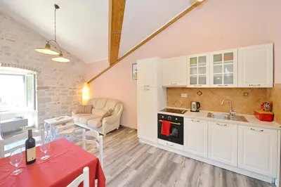 a kitchen with white cabinets and a table with a red table cloth at Old Town View - Sunny, Bright & Quiet in Kotor