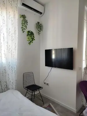 a bedroom with a tv on the wall and a chair at Studio apartment, 5 minutes to the beach in Bar