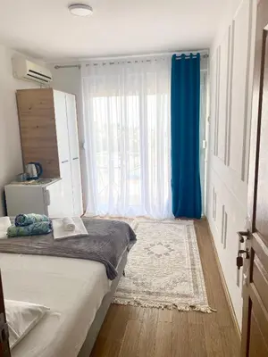 a bedroom with a bed with a blue curtain and a window at NOA Guest House in Ulcinj