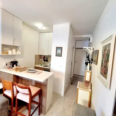a kitchen with white cabinets and a counter and chairs at Apartman Podgorica in Podgorica