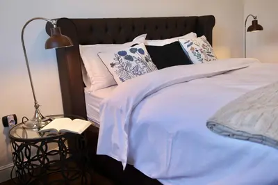 a bed with white sheets and pillows and a lamp at Home Filip in Golubovci