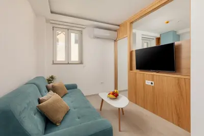 a living room with a blue couch and a tv at Ocea Studio Apartments in Kotor