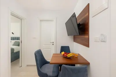a dining room with a wooden table and blue chairs at Ocea Studio Apartments in Kotor