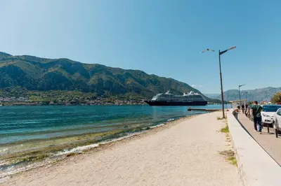 a beach with a cruise ship in the water at Ocea Studio Apartments in Kotor