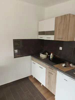 a kitchen with white cabinets and a black counter top at Crni Bor Sutomore in Sutomore