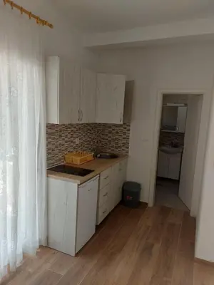 a kitchen with white cabinets and a wooden floor at Crni Bor Sutomore in Sutomore