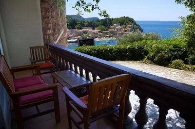 two chairs and a table on a balcony overlooking the ocean at Villa Sara Guesthouse in Sveti Stefan