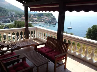 a balcony with two chairs and a view of the water at Villa Sara Guesthouse in Sveti Stefan