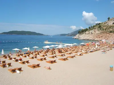 a beach with a lot of chairs and people on it at Villa Sara Guesthouse in Sveti Stefan