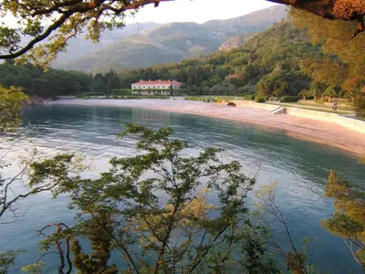 a beach with a building in the middle of a river at Villa Sara Guesthouse in Sveti Stefan