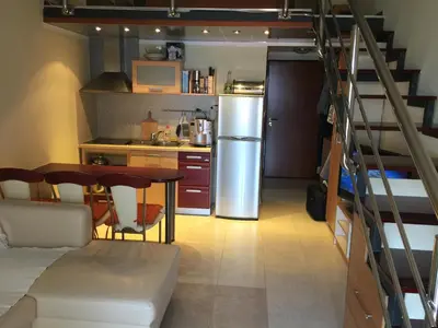 a kitchen with a staircase and a table and a refrigerator at Villa Sara Guesthouse in Sveti Stefan