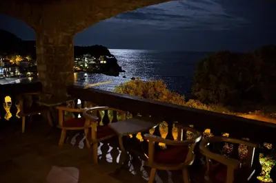 a balcony with chairs and a view of the ocean at night at Villa Sara Guesthouse in Sveti Stefan