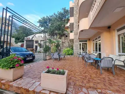 a patio with tables and chairs and a car parked at Violit Apartments&Restaurant in Sutomore