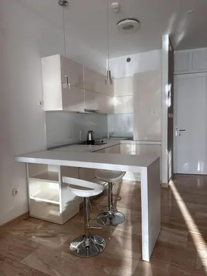 a white kitchen with a counter and stools at TC BiG APARTMENTS in Budva
