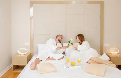 a man and a woman sitting on a bed at TC BiG APARTMENTS in Budva