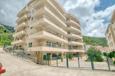 a large apartment building with a fence in front of it at Blue Lagoon in Petrovac na Moru