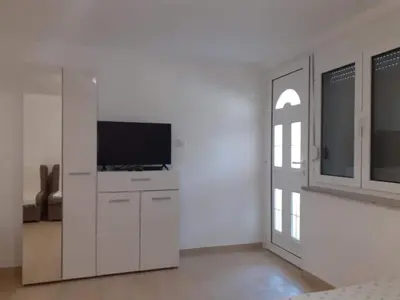 a living room with a tv and a white wall at Apartmani Roki in Tivat