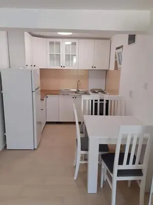 a kitchen with white cabinets and a table and chairs at Apartmani Roki in Tivat