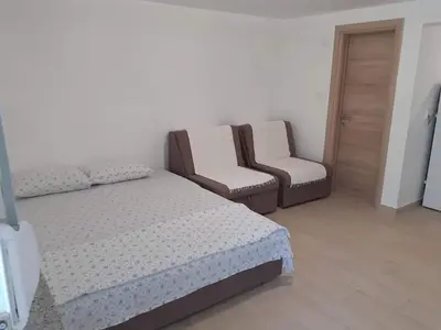 a bedroom with a bed and a couch and a chair at Apartmani Roki in Tivat