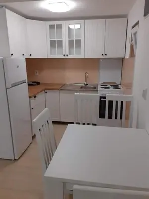 a kitchen with white cabinets and a sink and a table at Apartmani Roki in Tivat