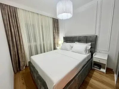 a bedroom with a large white bed and a chandelier at Apartments Doclea in Podgorica
