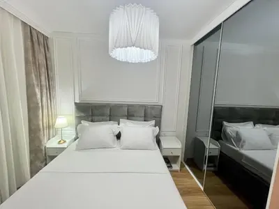 a bedroom with a large white bed and a chandelier at Apartments Doclea in Podgorica