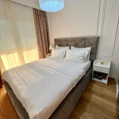 a bedroom with a large bed with white sheets and pillows at Apartments Doclea in Podgorica