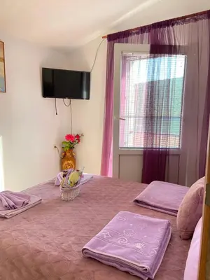 a bedroom with a bed with purple sheets and a window at Apartment Alex in Kotor