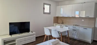 a white kitchen with a table and a tv at APARTMANI NINI in Rafailovici