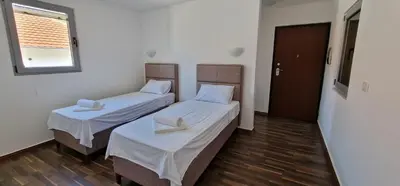 two beds in a small room with a window at APARTMANI NINI in Rafailovici