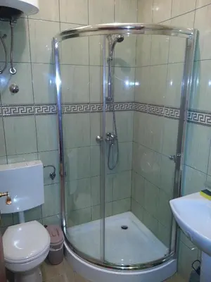 a bathroom with a shower with a toilet and a sink at Guest House Pansion 10 in Cetinje