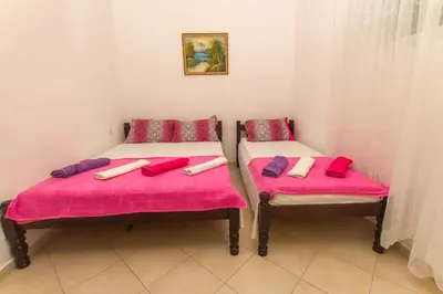 two beds with pink cushions in a room at Apartments Petković in Petrovac na Moru