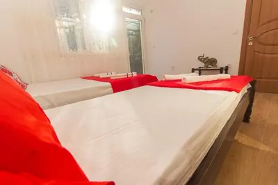 two beds in a room with red and white sheets at Apartments Petković in Petrovac na Moru