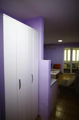 a room with white cabinets and a living room at Sutomore apartman in Sutomore