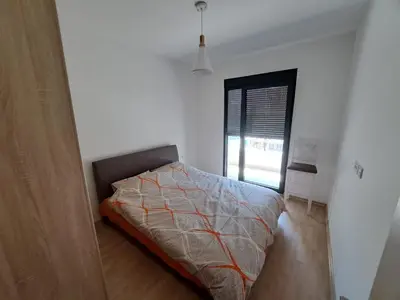 a white bedroom with a bed and a window at Home Away Apartment in Podgorica